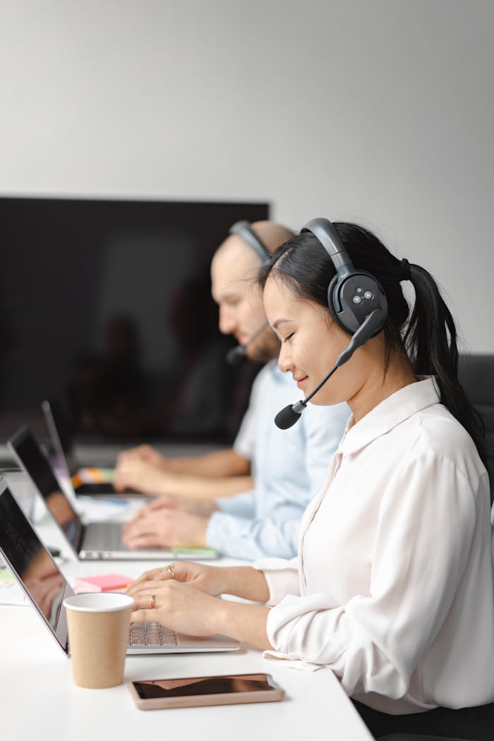 services-04 A diverse group of call center agents wearing headsets and working on laptops indoors.