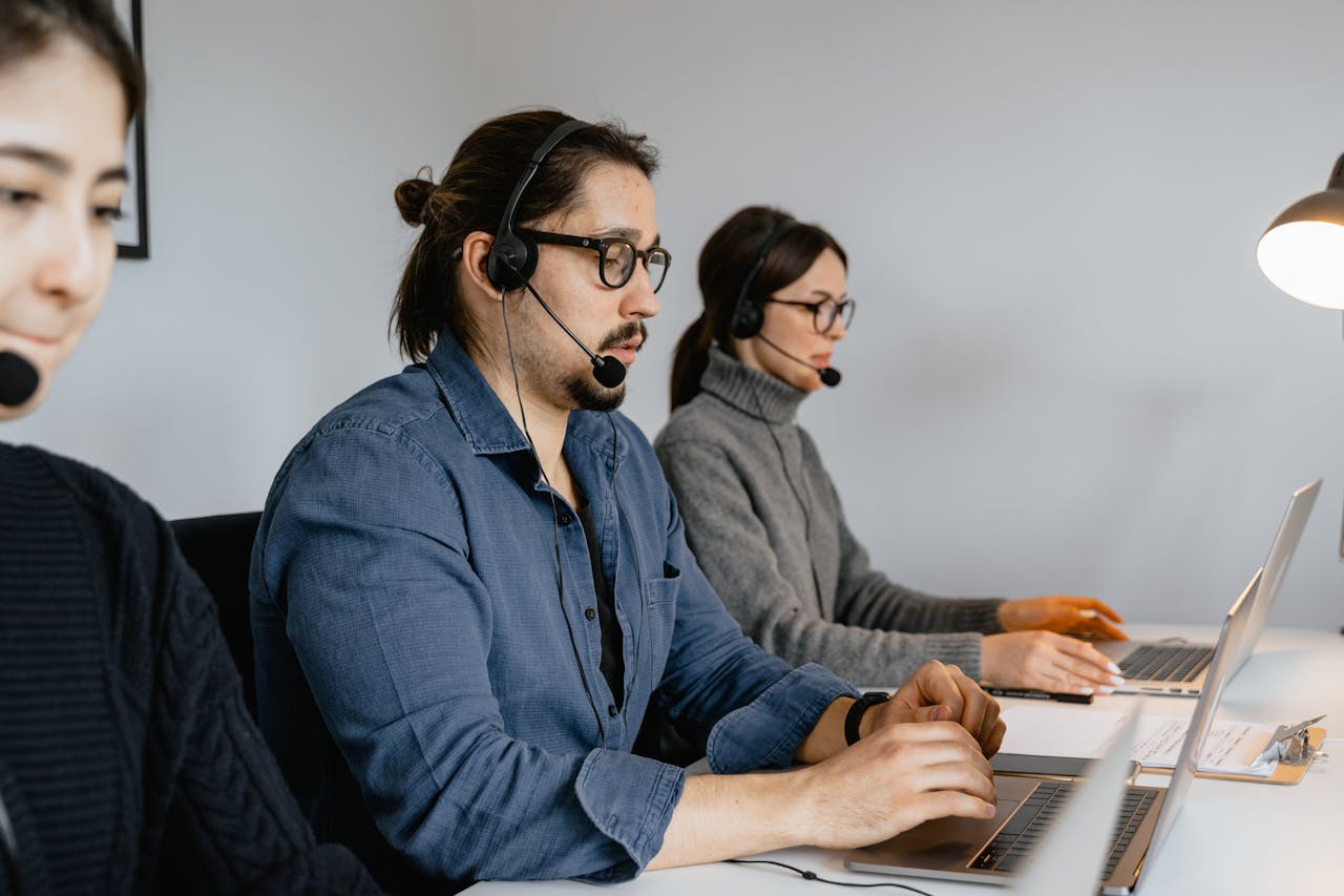 Customer service team at call center using laptops and headsets.