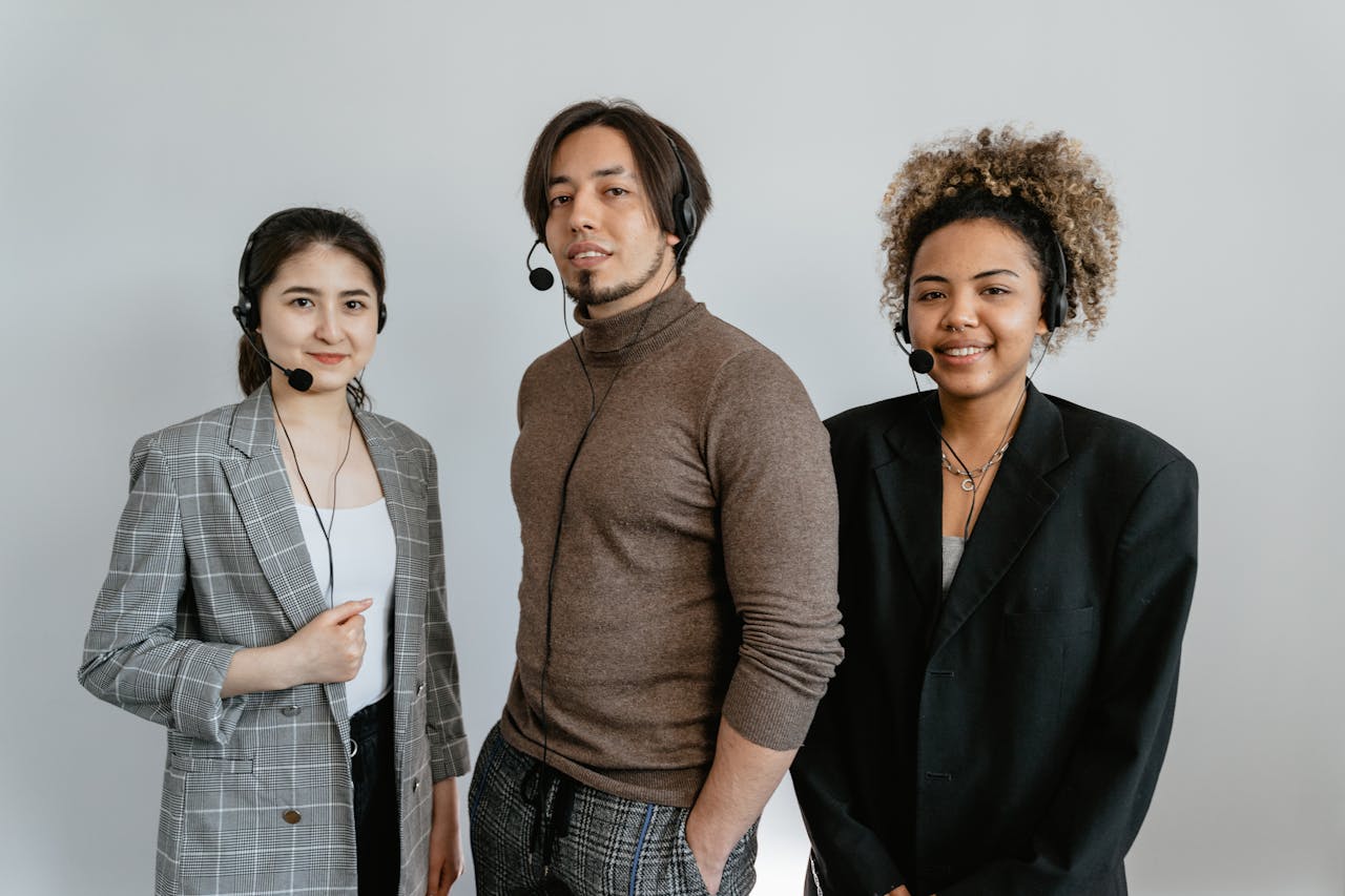 Three diverse customer support representatives wearing headsets and standing together.